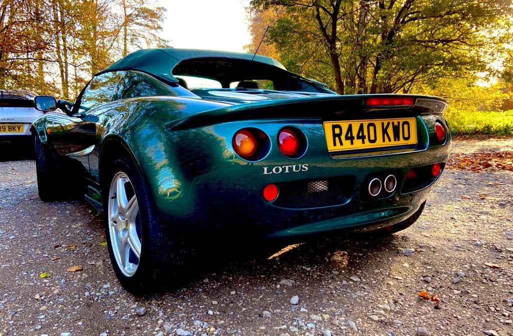 A green S1 Lotus Elise parked, and photographed from the nearside rear three-quarter angle