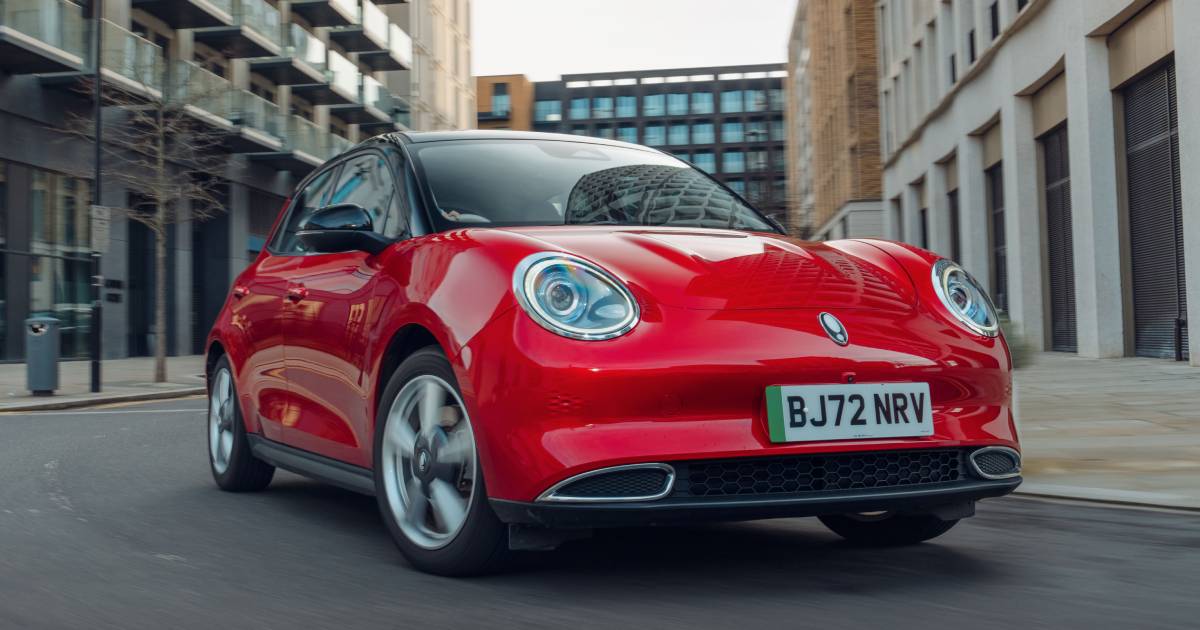 A red Ora 03 electric car, photographed, in motion, from the front 3/4 in the city