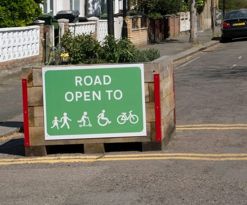 A green sign displaying icons of pedestrians, a scooter rider, a wheelchair user and a bicycle, together with the words 'road open to'.