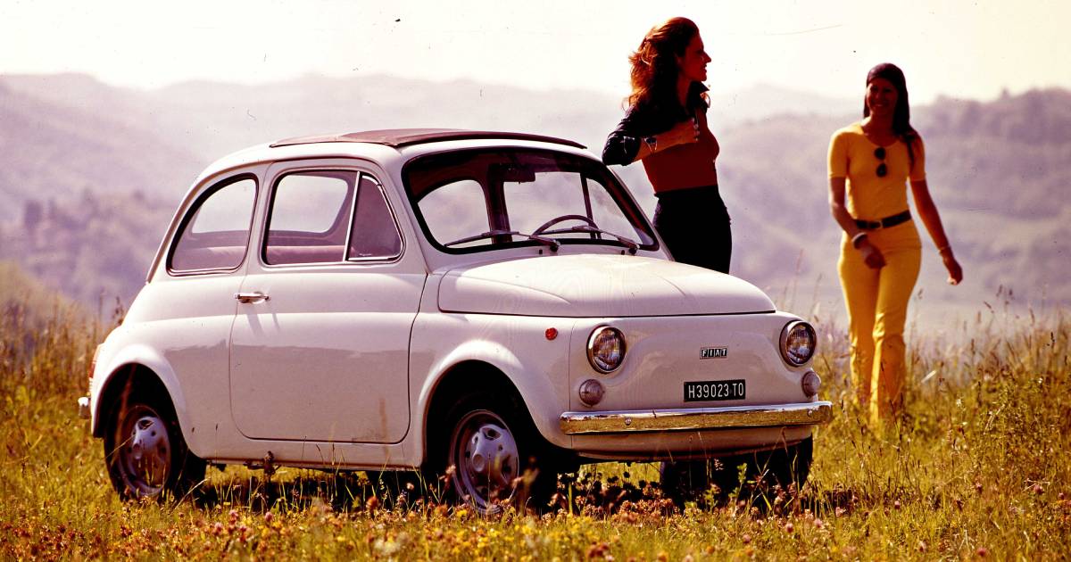 A white original Fiat 500 parked on grass with two women wearing 1970s clothes