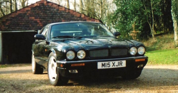 A black Jaguar XJR parked on a driveway in the 1990s; the number plate reads MI5 XJR